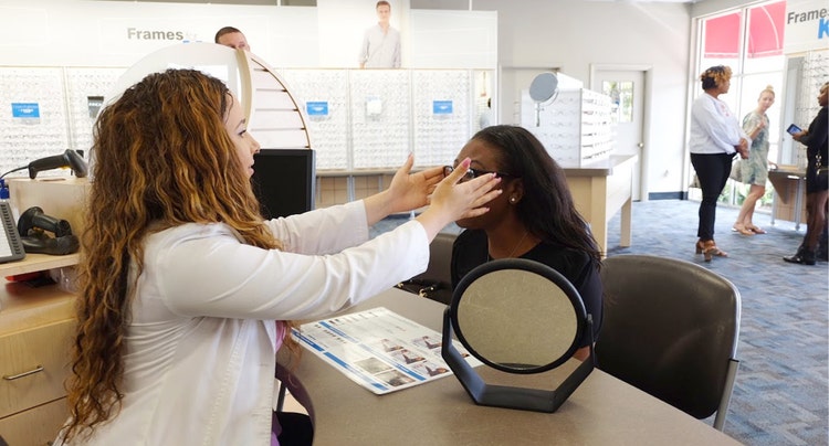 Woman getting eyeglasses adjusted in an Eyeglass World store