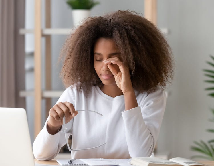 Woman rubbing irritated eyes while looking at a computer